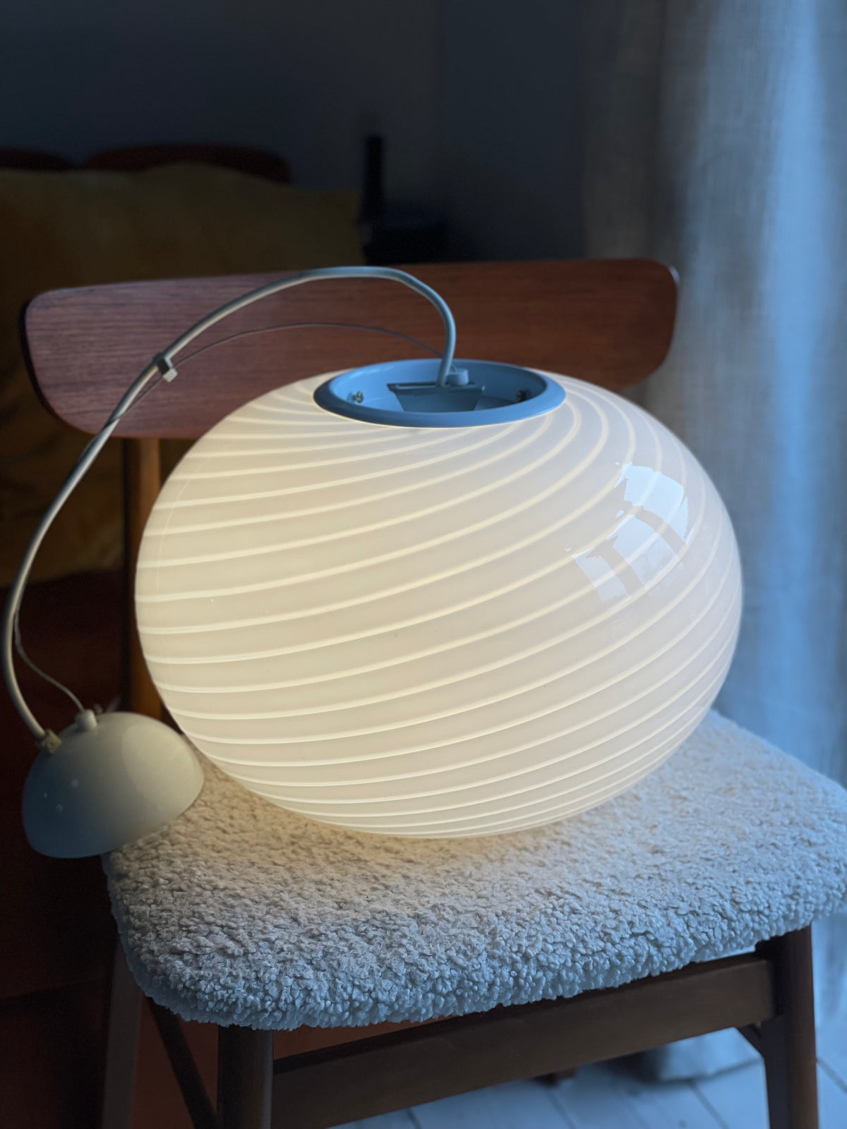 Tændt hvid vintage Murano pendel med swirl-mønster på en stol med uldsæde